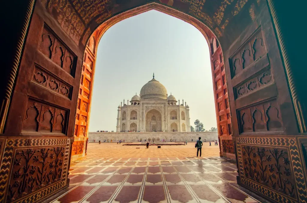 India Tour Packages 6 "Tourists enjoying the view of the Taj Mahal from an arched gateway during their Luxury Golden Triangle Tour in India."