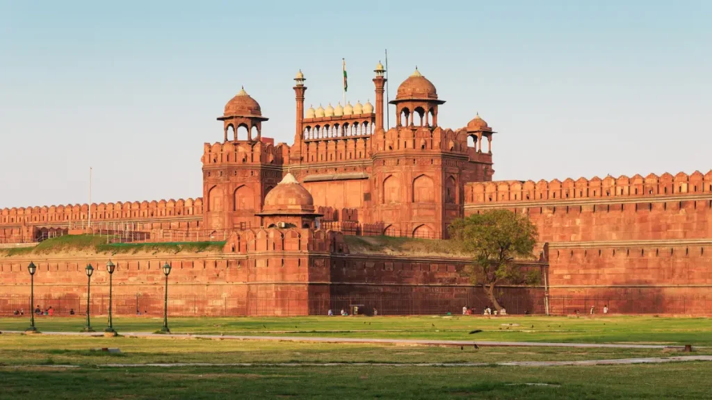 What is the best time to visit Delhi? 1 View of the Red Fort in Delhi, a grand Mughal-era fortress made of red sandstone, featuring domed towers, high walls, and the Indian flag atop the main gate.
