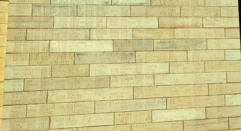 Close-up image of engraved names on the walls of the India Gate war memorial in New Delhi, India. The sandstone blocks bear the names of Indian soldiers who died in World War I and the Third Anglo-Afghan War. The inscriptions include ranks, names, and regiments, such as "112th Infantry," "90th Punjabis," and "117th Mahrattas," honoring the memory of the fallen.