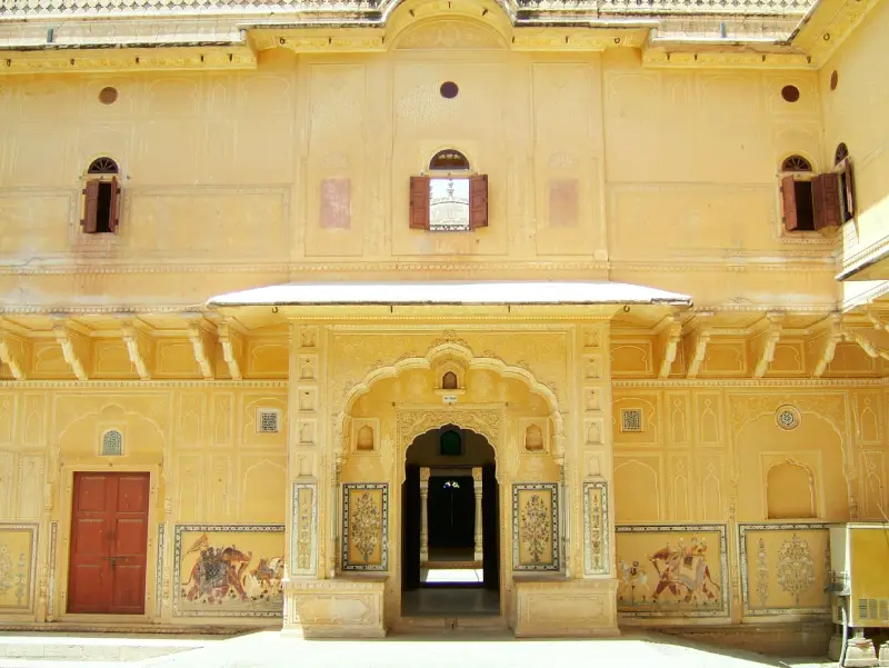 Nahargarh Fort 2 "Ornate yellow sandstone facade inside the Nahargarh Fort in Jaipur, featuring arched doorways, traditional Rajasthani frescoes, and small wooden windows."