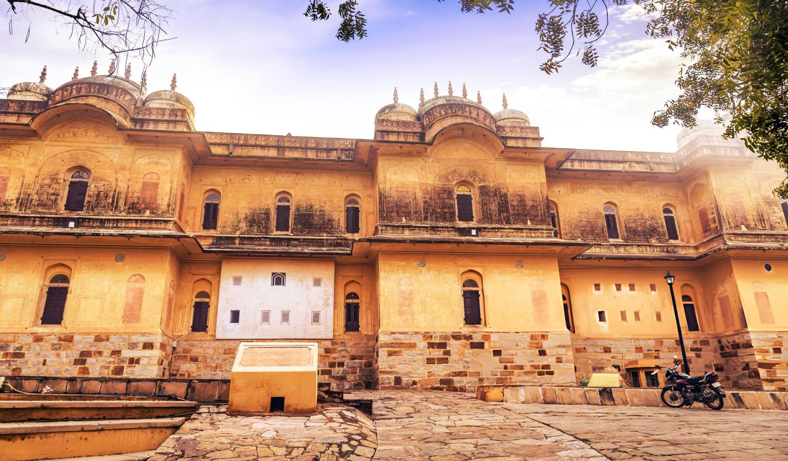 A historic yellow sandstone building with intricate architecture, photographed on a sunny day, showcasing the beauty of India’s cultural heritage. Travel With Vasco’s India Group Tour guests explored this iconic site during their India tour service.